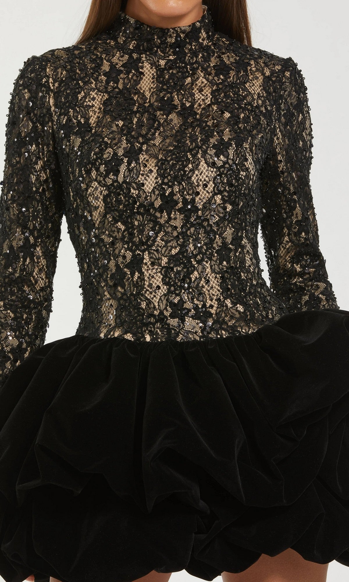 A person wearing the Mac Duggal 21175 short semi-formal dress—a black lace long-sleeve cocktail style with a high mock-neck and voluminous velvet bubble mini skirt.